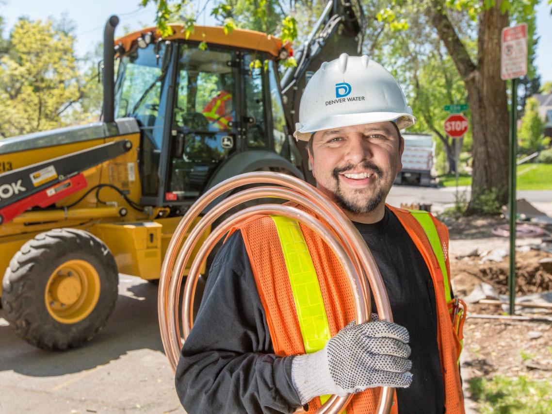 Man in front of machinery with Denver Water hard hat