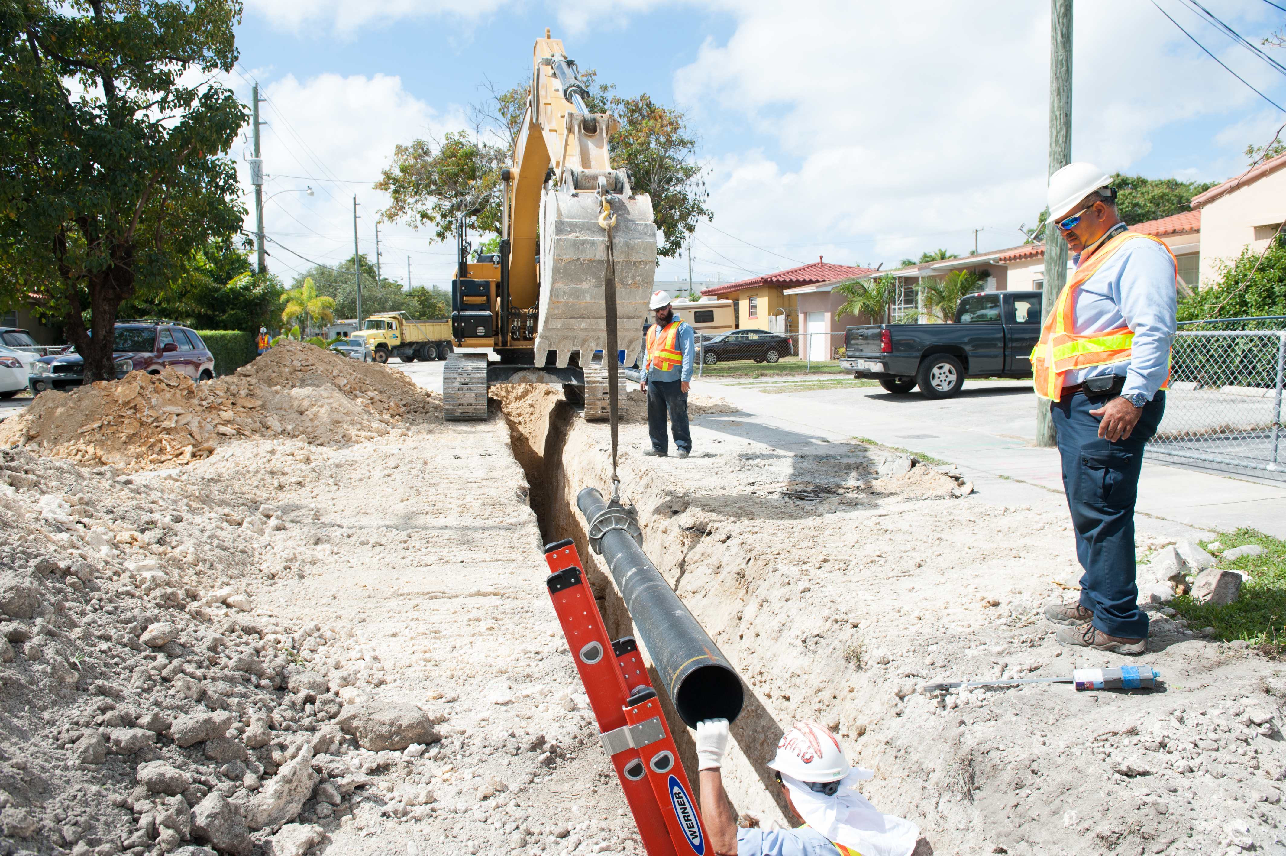 Workers looking at water pipe in ground